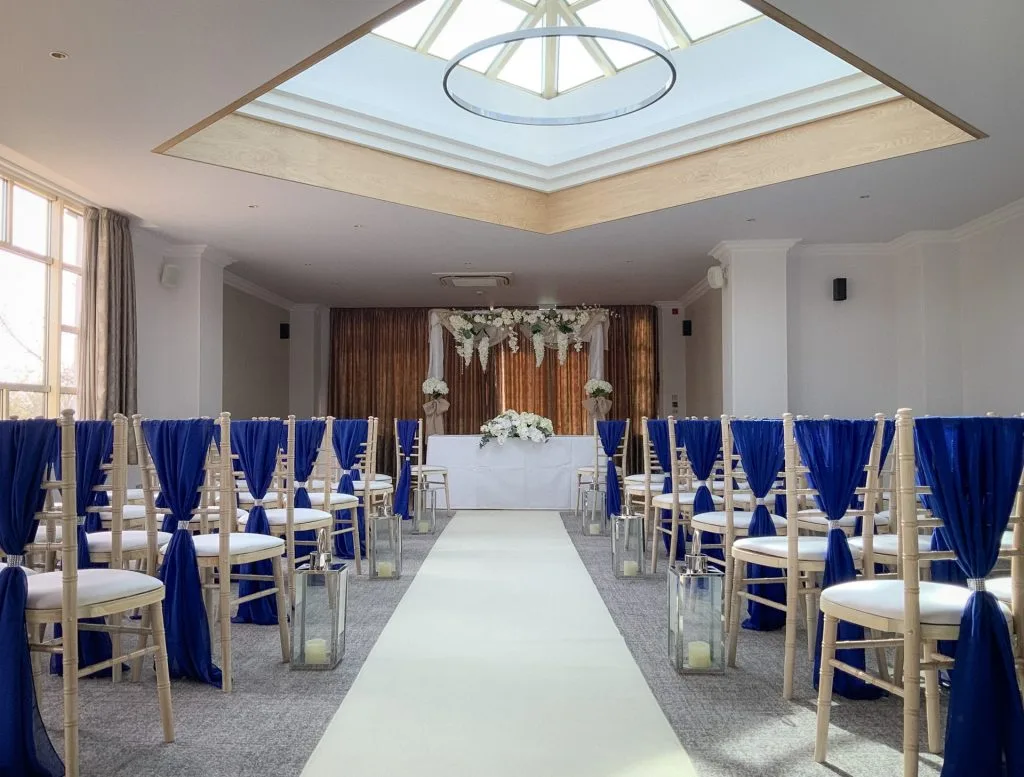 Wedding aisle in a venue with a skylight overhead, lined with chairs on either side