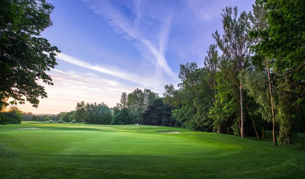 18 hole golf course Milton Keynes with a fairway under clear blue skies.