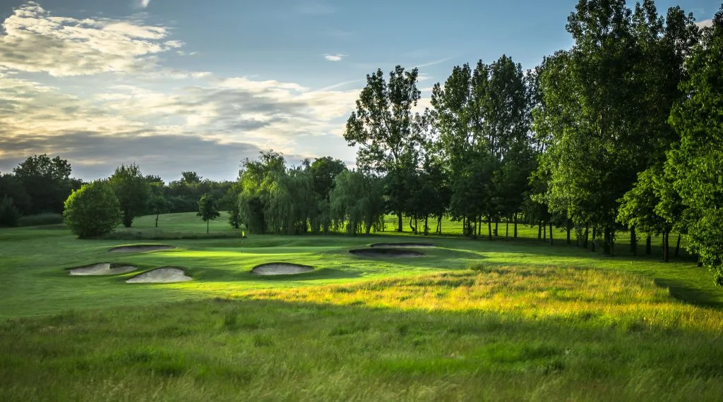 Golf course in Milton Keynes with wavy rough and several bunkers at sunset