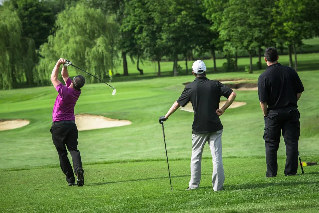 Group of golfers at golf club Milton Keynes watching an approach shot onto the green during golf days Milton Keynes
