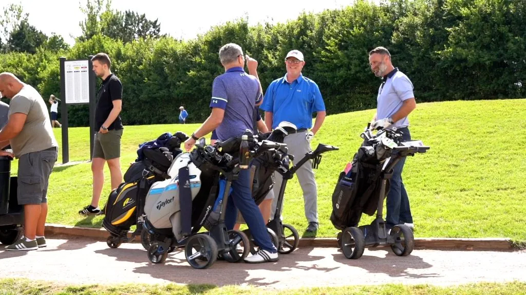 Group of golfers talking near a tee box during a group golf day in Milton Keynes