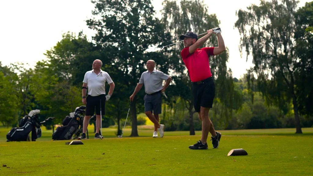 Golfers hitting balls off the tee at an 18 hole golf course in Milton Keynes, enjoying a golf day in Buckinghamshire