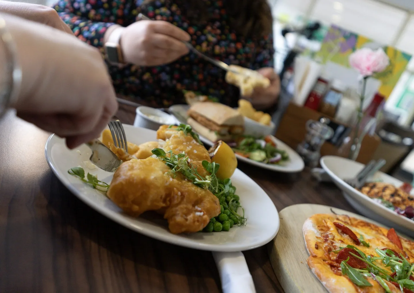 family enjoying food, cutting fish and chips at a restaurant near milton keynes