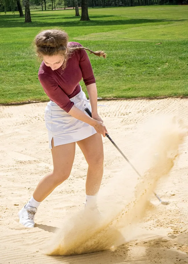 Golfer hitting out of a bunker at a Milton Keynes golf course, practicing golf lessons and improving technique.