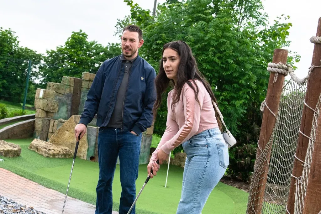 couple playing crazy golf together looking focused