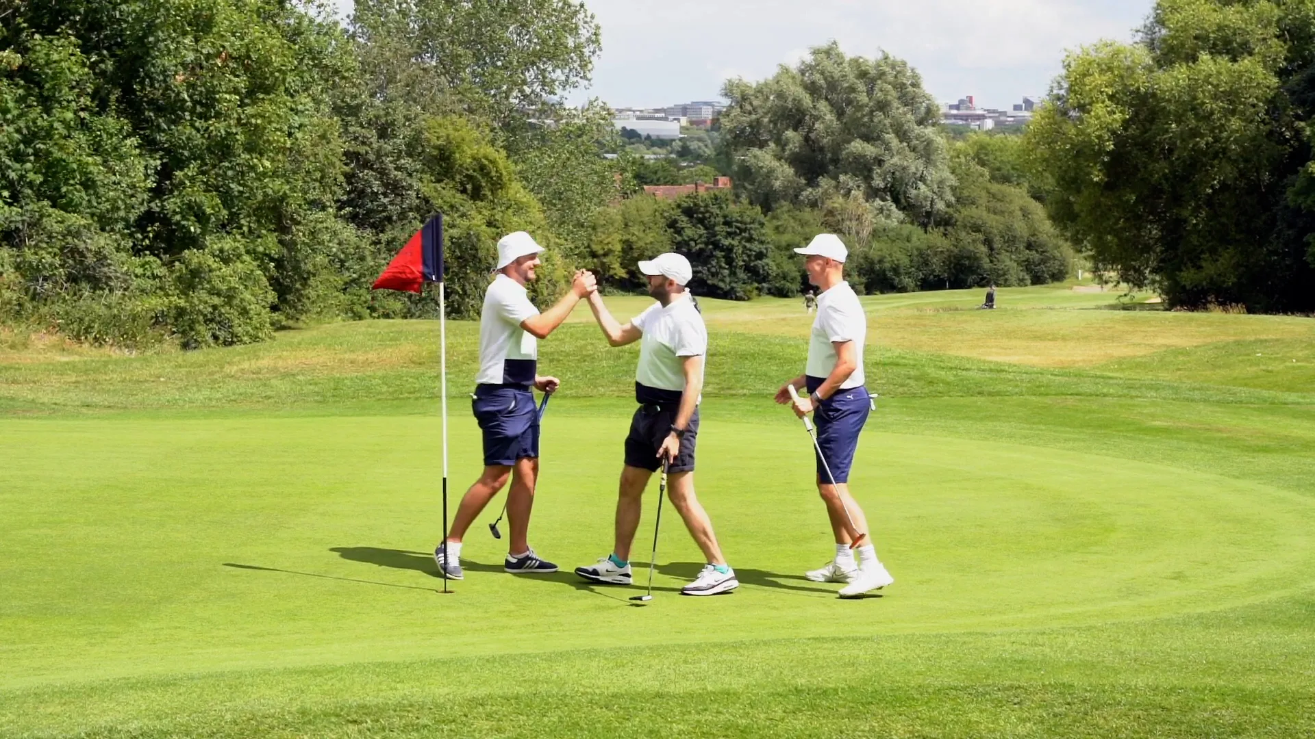 Three golfers handshaking on the green at a golf club after a golf day, celebrating their golf society day in Milton Keynes