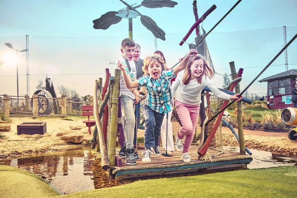 Family laughing and smiling while playing mini golf at a golf club in Milton Keynes