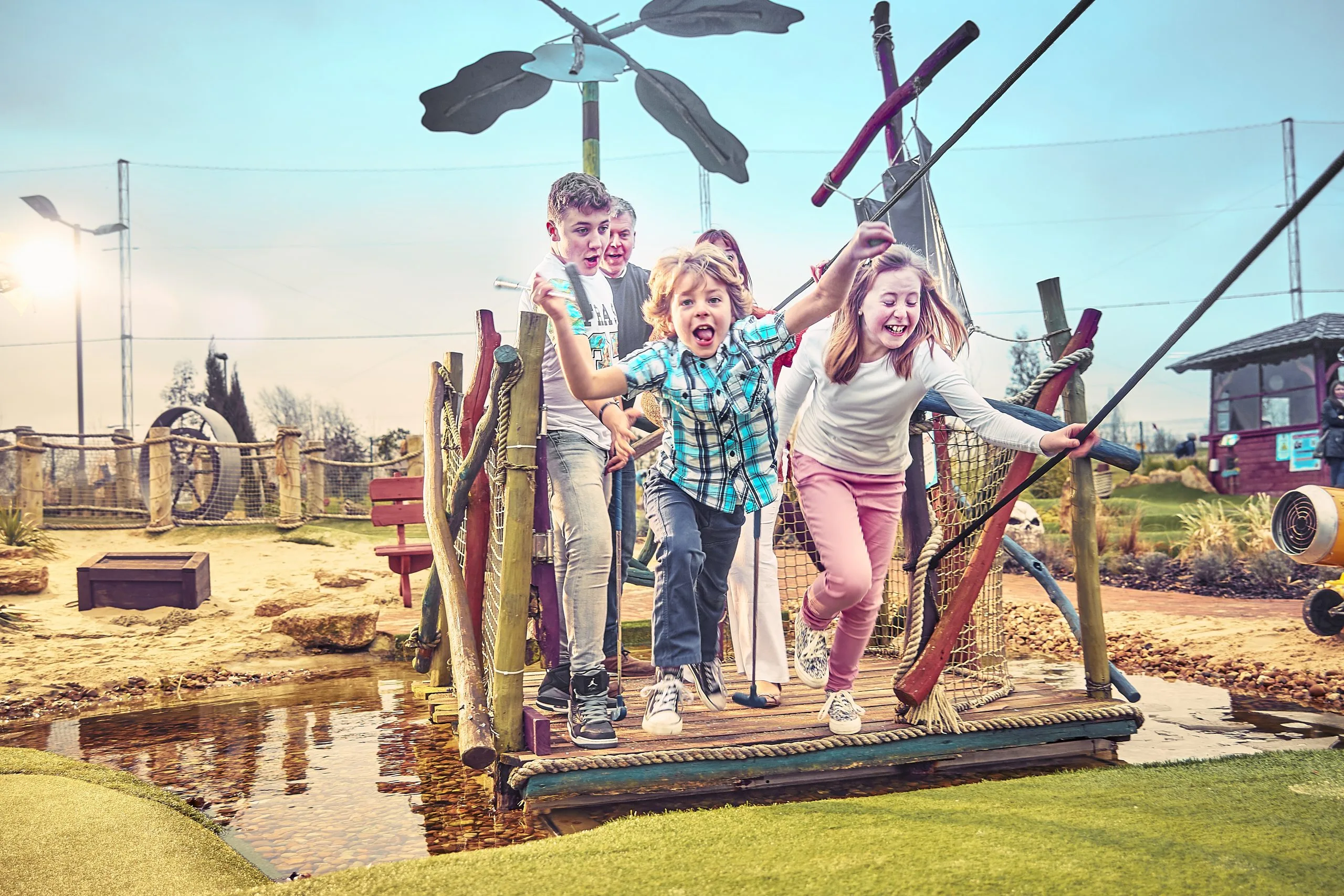 Family laughing and smiling while playing mini golf at a golf club in Milton Keynes