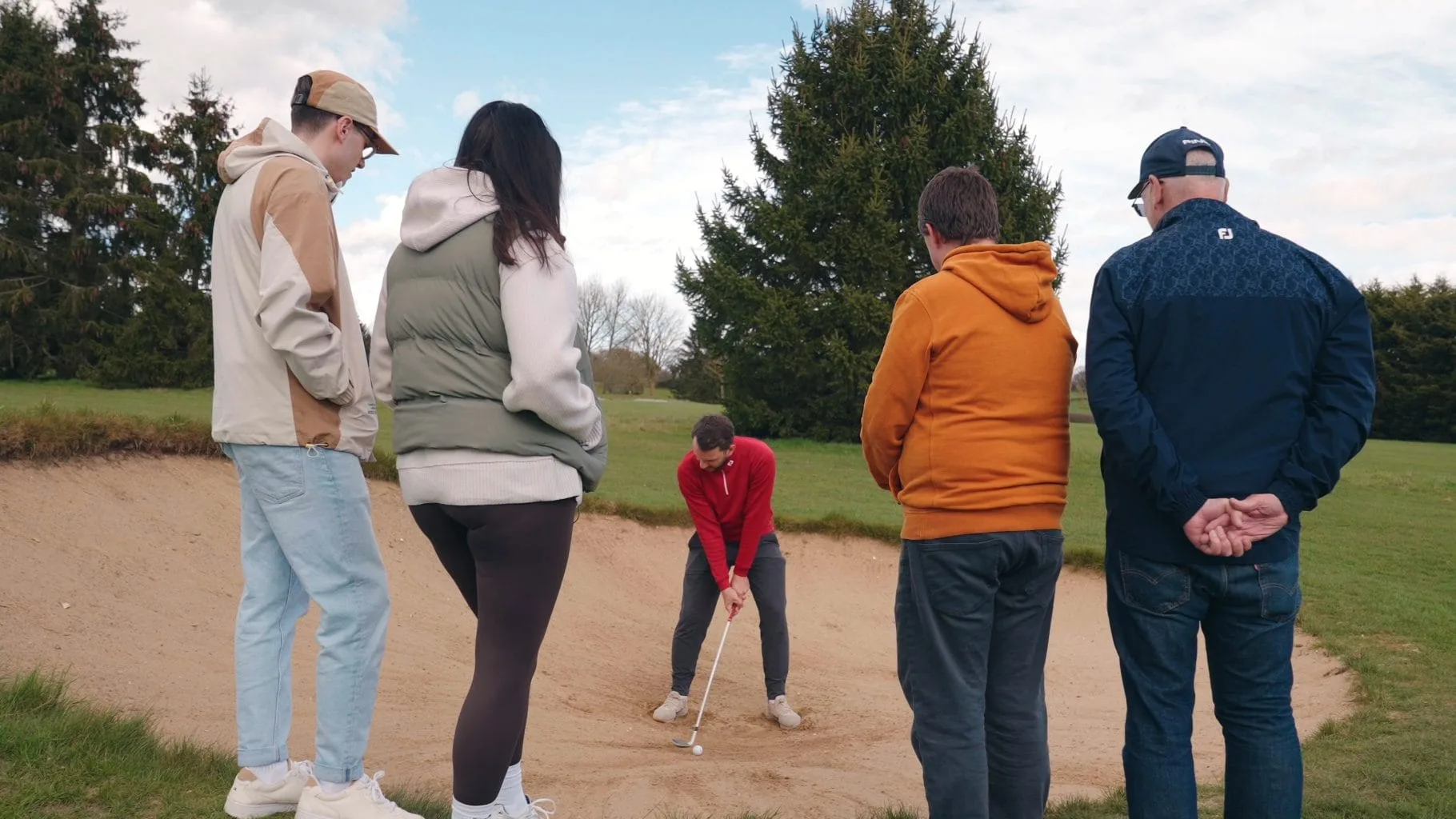 Group golf lesson in Milton Keynes with a PGA coach teaching beginners how to play bunker shots, part of golf lessons Buckinghamshire